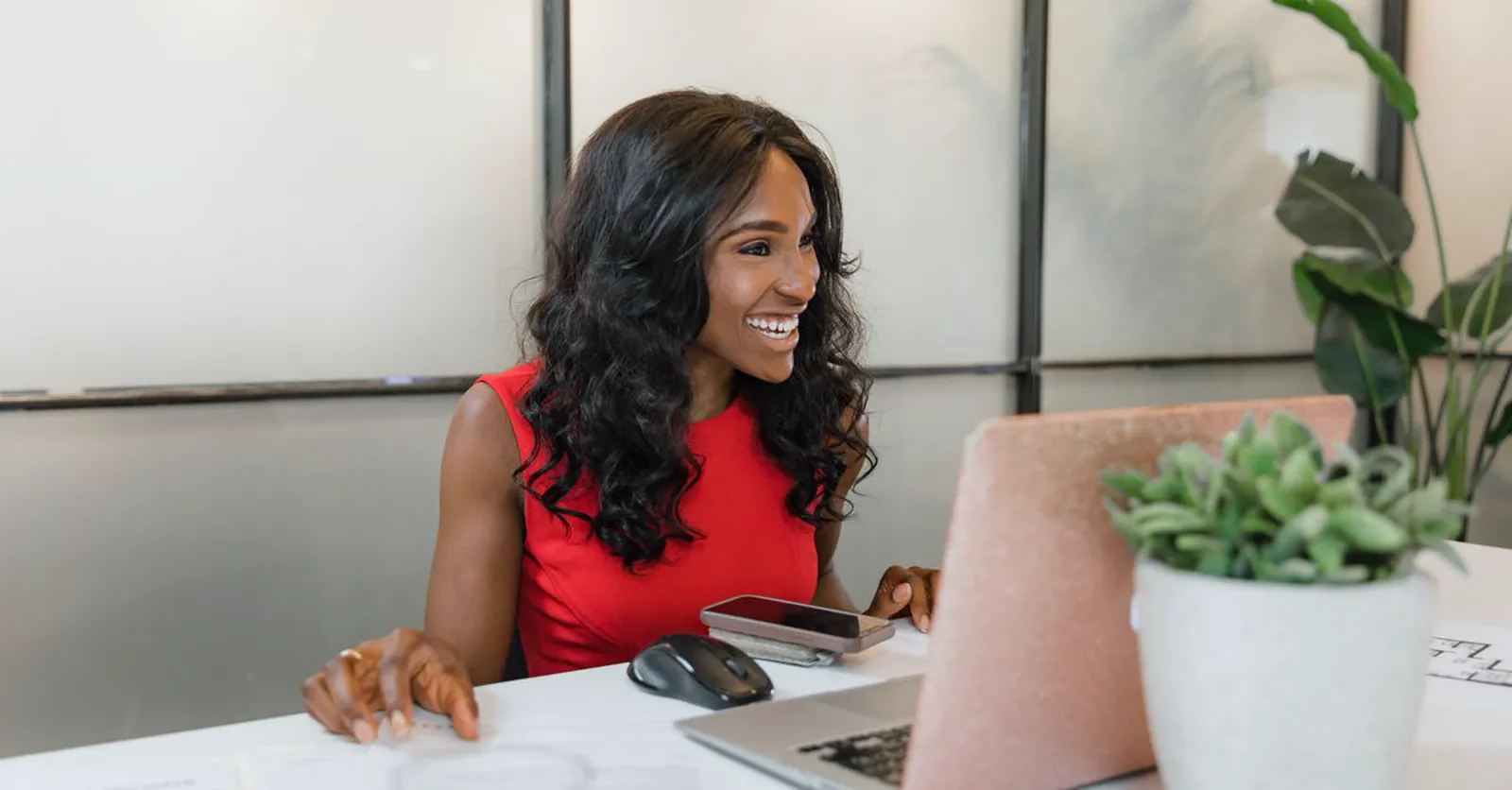 An African business owner smiling at a laptop while checking search results in an office.