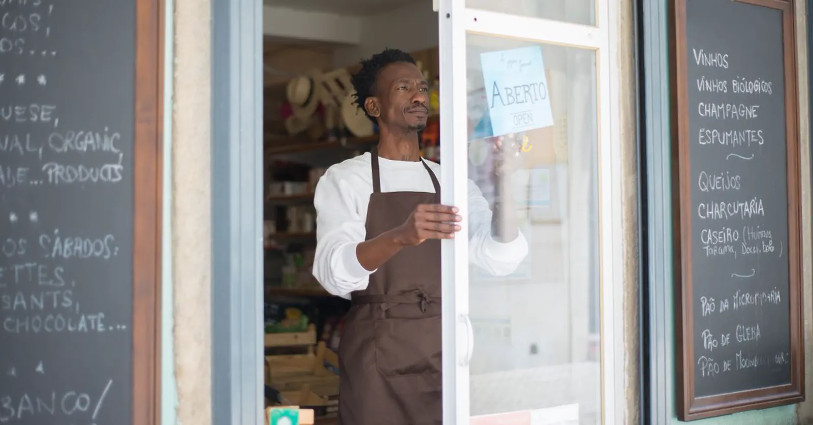 A shop owner turning the sign to Open at the door of his store.