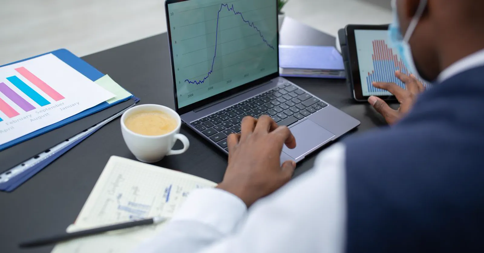 A business owner reviewing website traffic and analytics charts on a laptop and tablet.