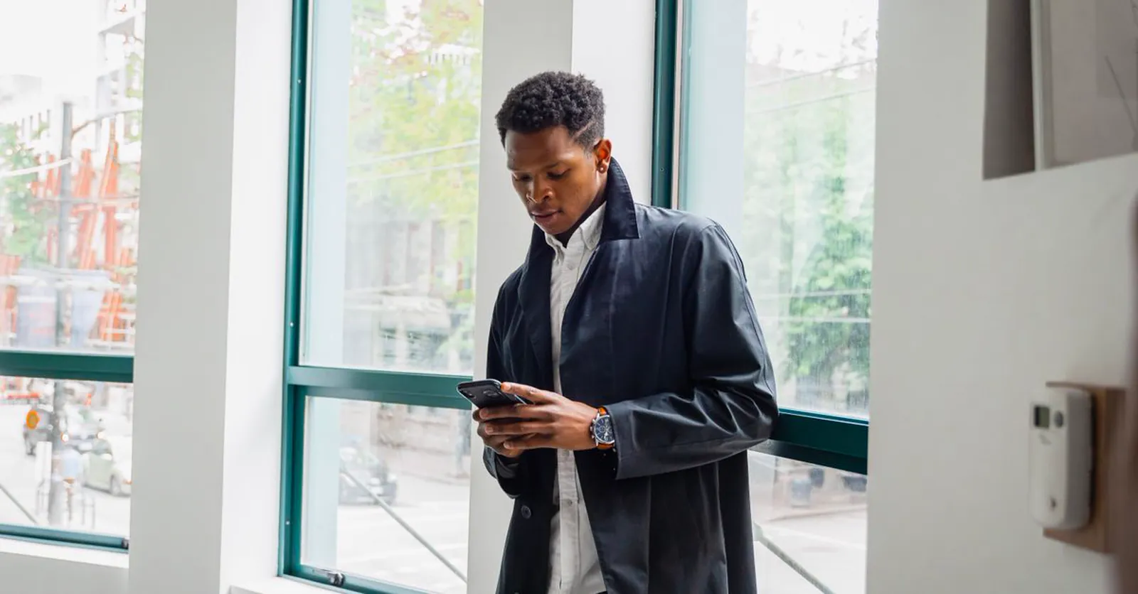 A professional checking his phone the way customers now ask an AI assistant a question.