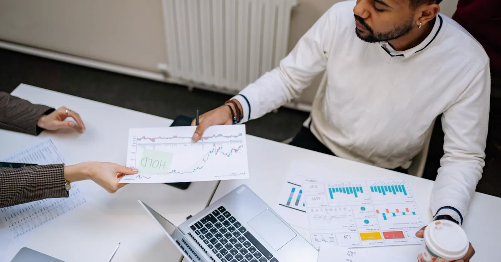 Two colleagues comparing performance charts and figures across a desk.