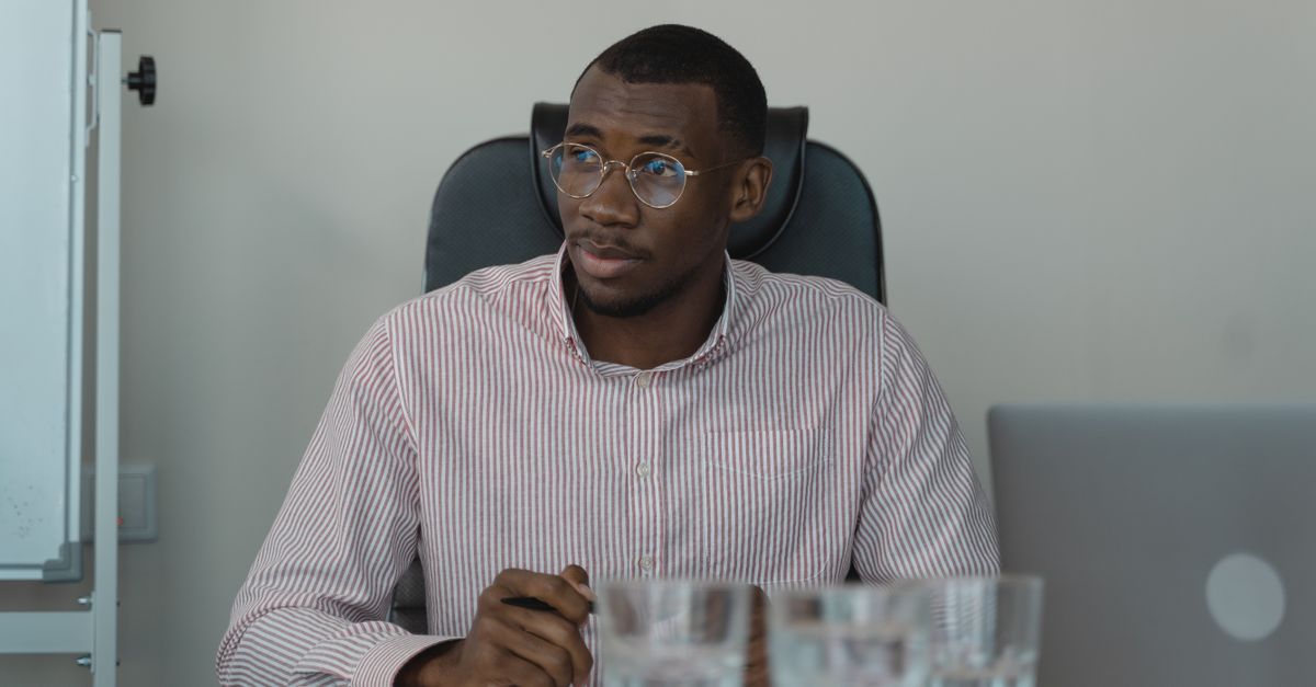 An African professional focused on work at a laptop in an office.